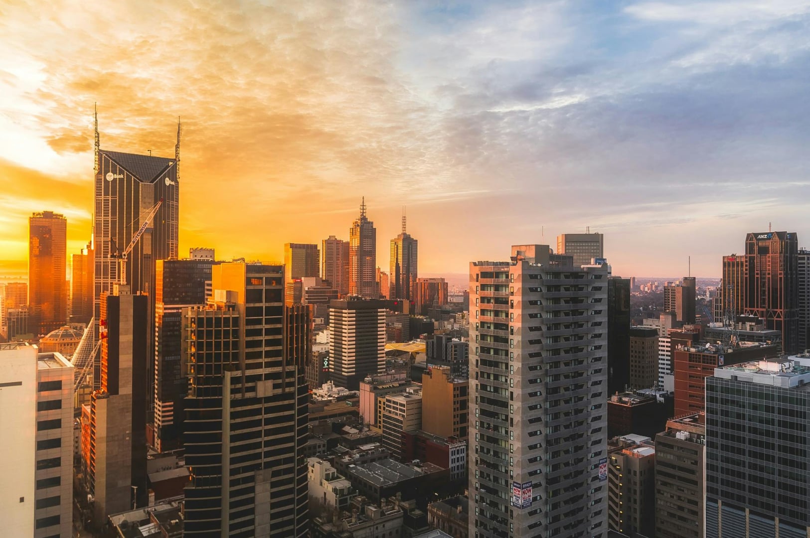 Melbourne city skyline at sunrise with modern skyscrapers bathed in warm golden light, Australia travel.
