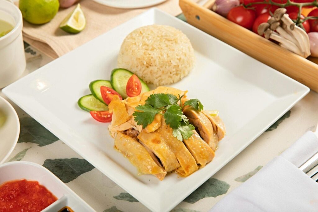 Authentic Singapore Hainanese Chicken Rice with seasoned rice and sliced cucumber.