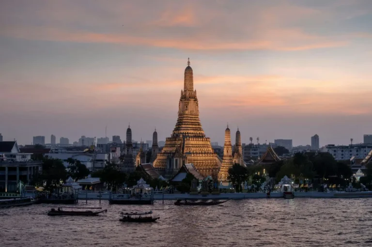 Wat Arun (Temple of Dawn) illuminated at sunset along the Chao Phraya River in Bangkok, Thailand.