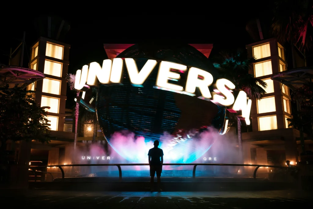 The iconic Universal globe is literally glowing at night, surrounded by these vibey pink and blue clouds of mist. A silhouette is just standing there taking it all in, making for the most main character energy photo op ever.