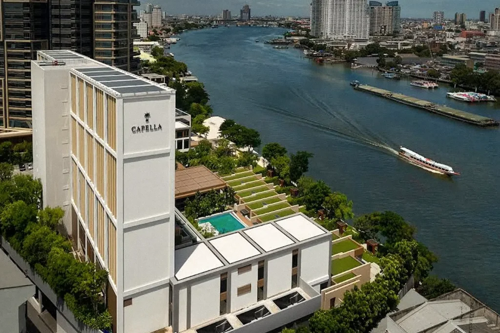 Aerial view of Capella Bangkok beside the Chao Phraya River, with its landscaped terraces and swimming pool overlooking the water.