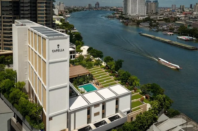 Aerial view of Capella Bangkok beside the Chao Phraya River, with its landscaped terraces and swimming pool overlooking the water.