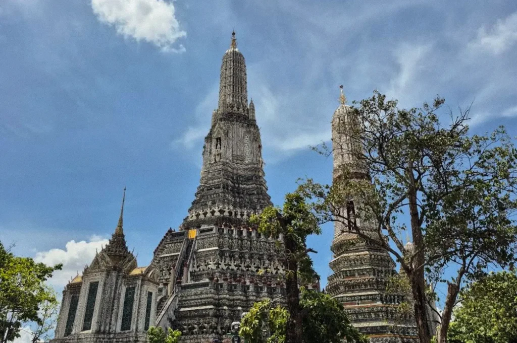 Close-up view of Wat Arun’s ornate temple towers and intricate floral mosaics under a bright blue sky.