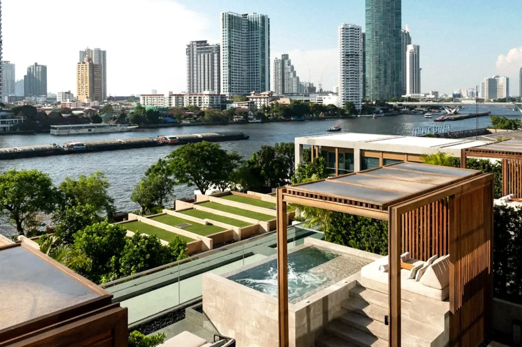 Rooftop hotel terrace overlooking the Chao Phraya River and Bangkok skyline, with a private plunge pool, lounge area, and landscaped gardens.