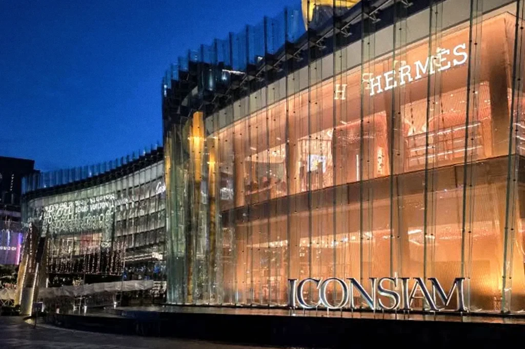 Glass-fronted shopping and dining complex illuminated at night, with the “ICONSIAM” sign visible along the building exterior.