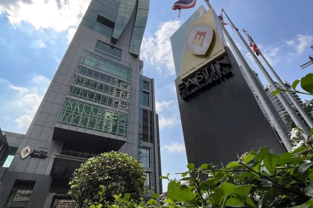 Exterior view of Eastin Grand Hotel Sathorn, showing the modern hotel building and roadside sign beneath a bright blue sky.